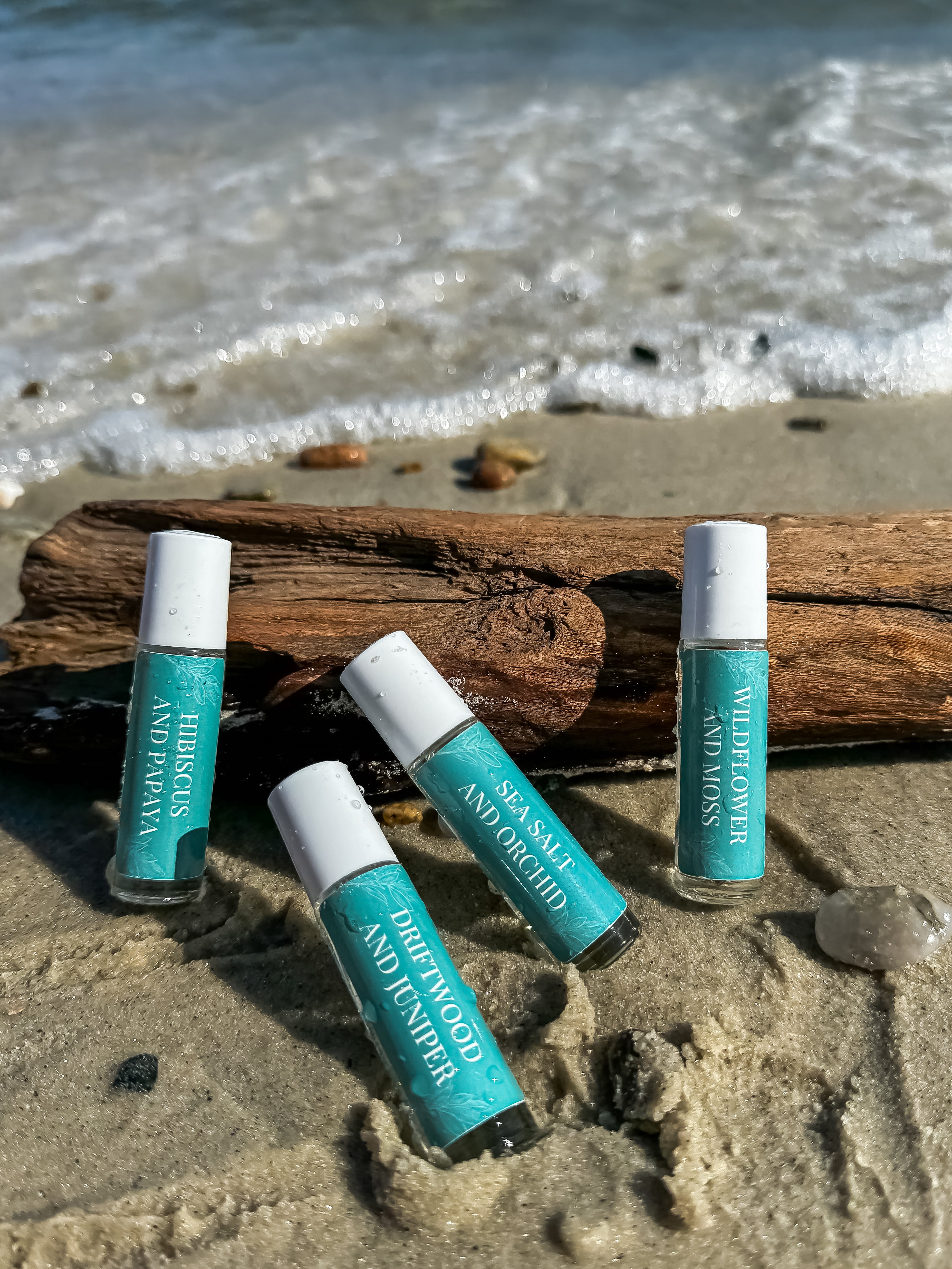 Salt and Branch teal rollerball perfumes laying on driftwood