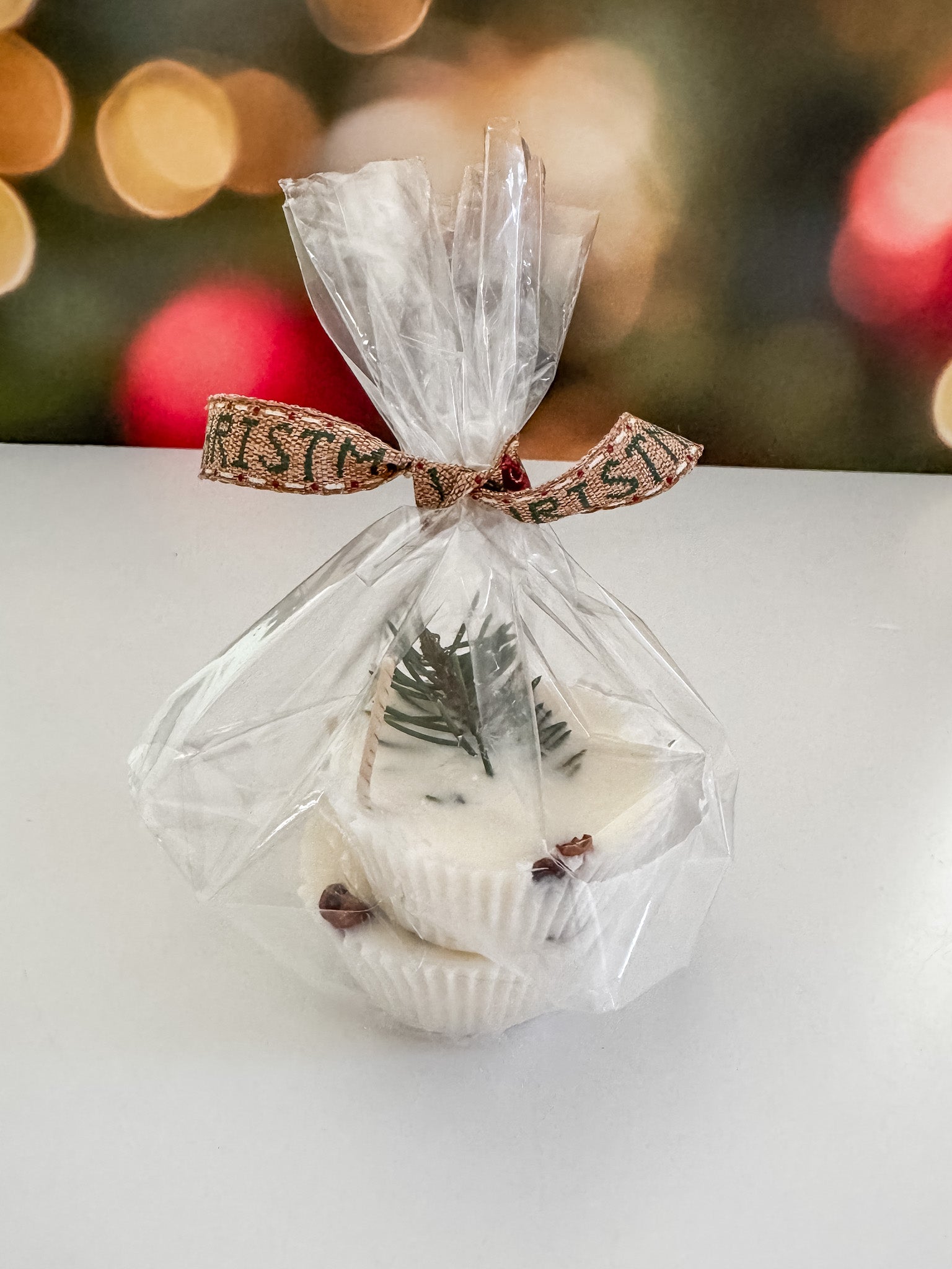 Clear gift bag with 2 soy wax fire starters on a white surface with blurred festive background