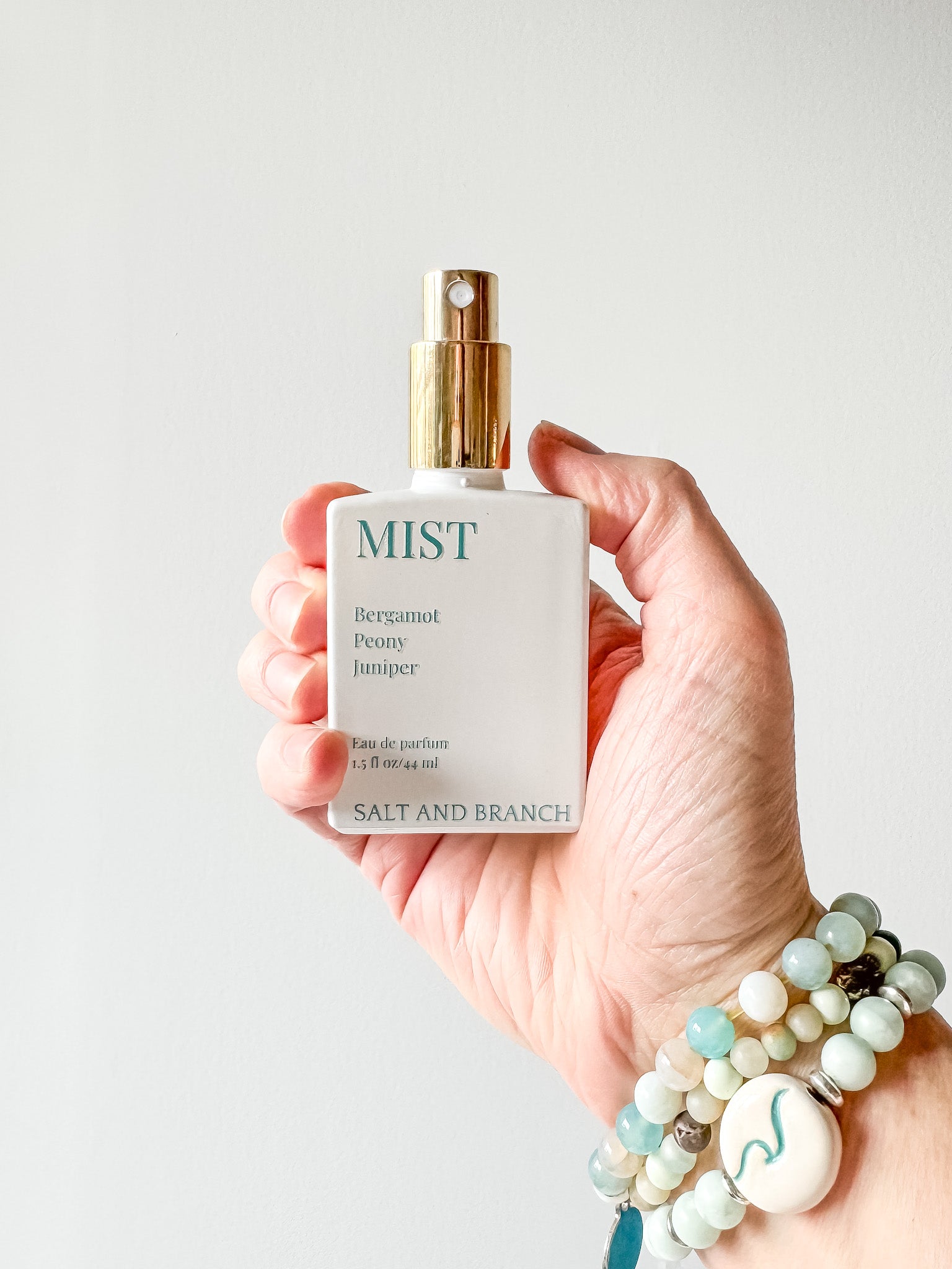 Hand holding a bottle of 'MIST' by Salt and Branch against a plain background