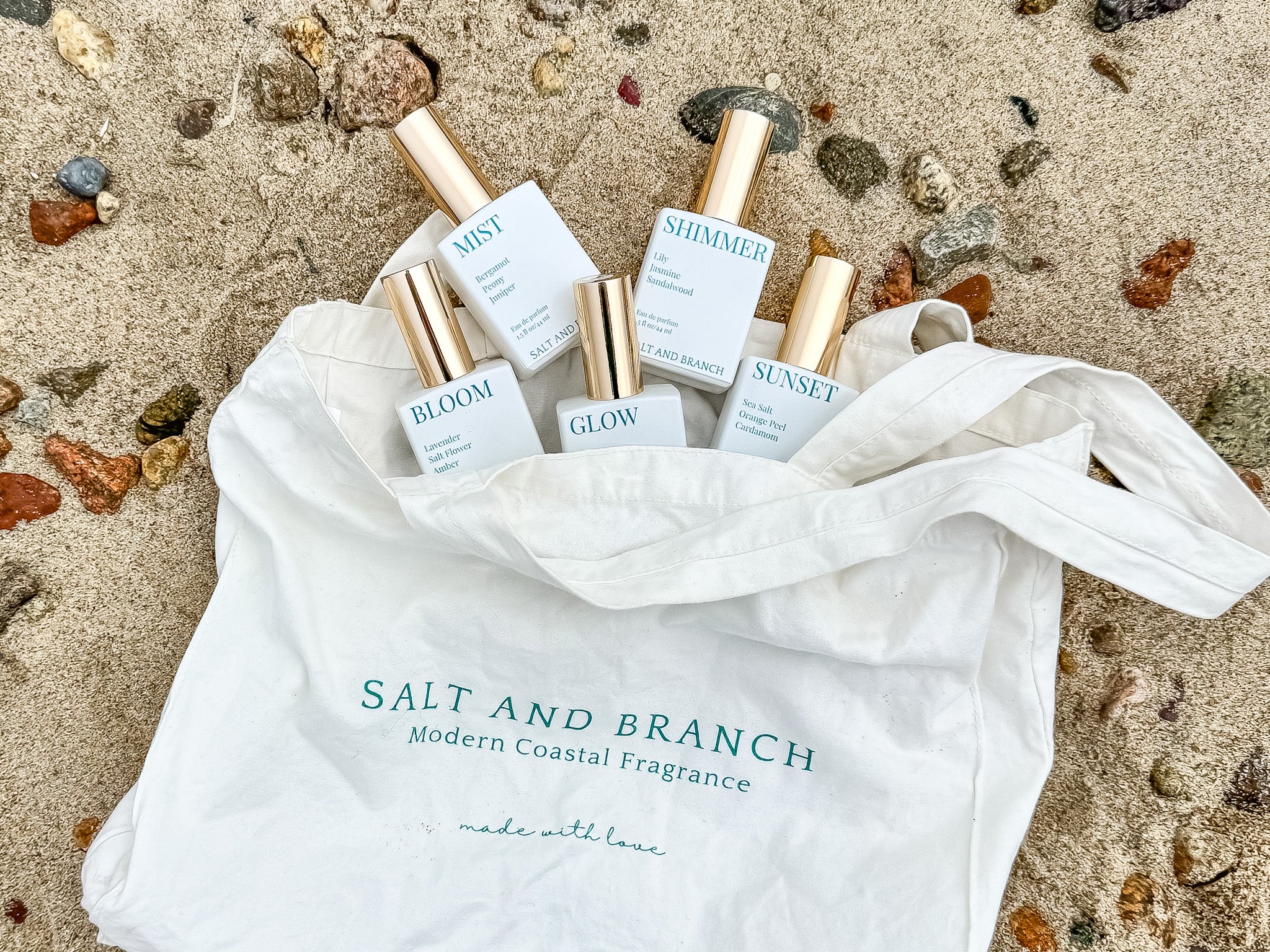 white and gold perfume bottles on beach Salt and branch