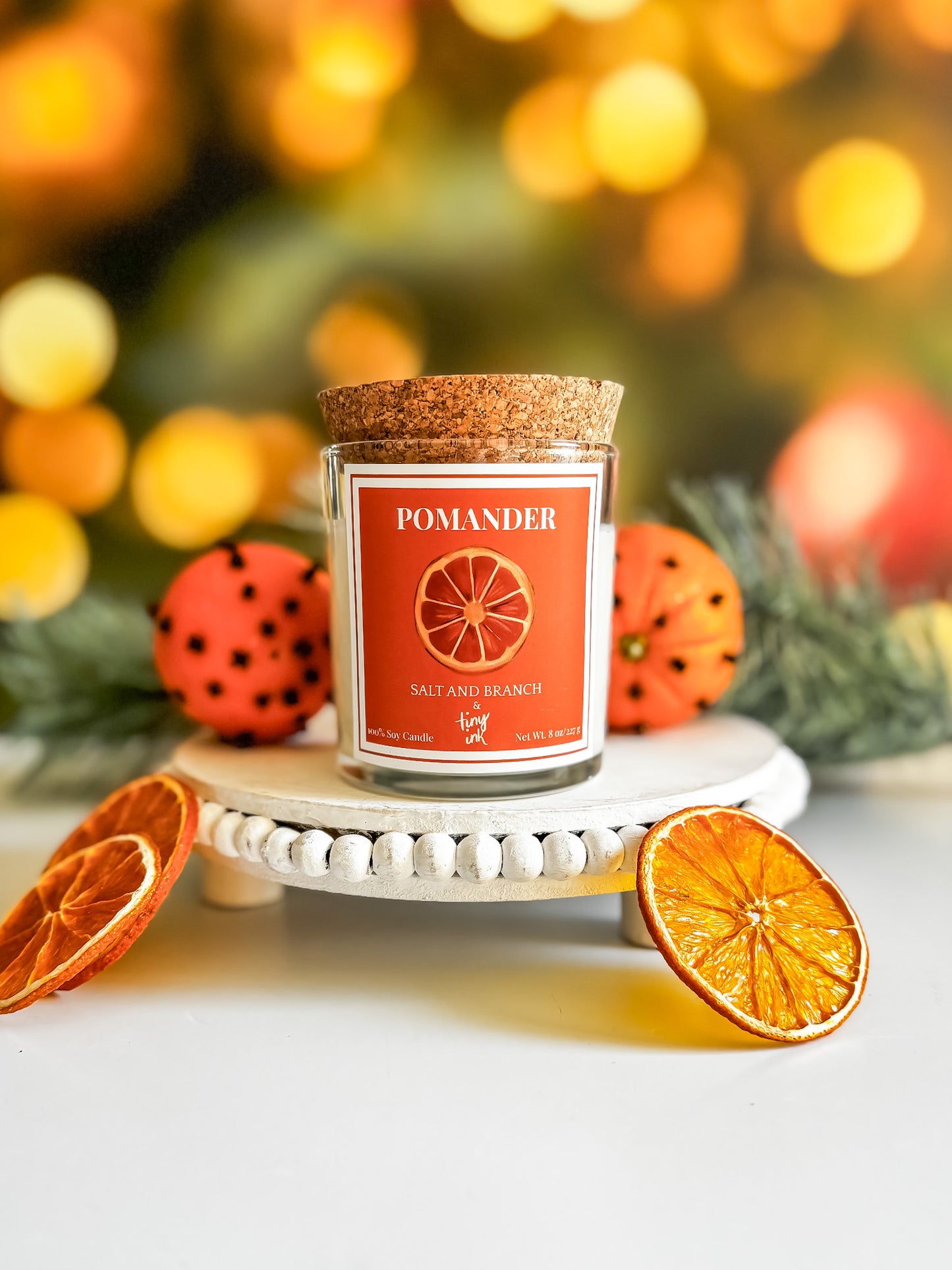 Pomander candle with dried oranges on a decorative stand against a festive background