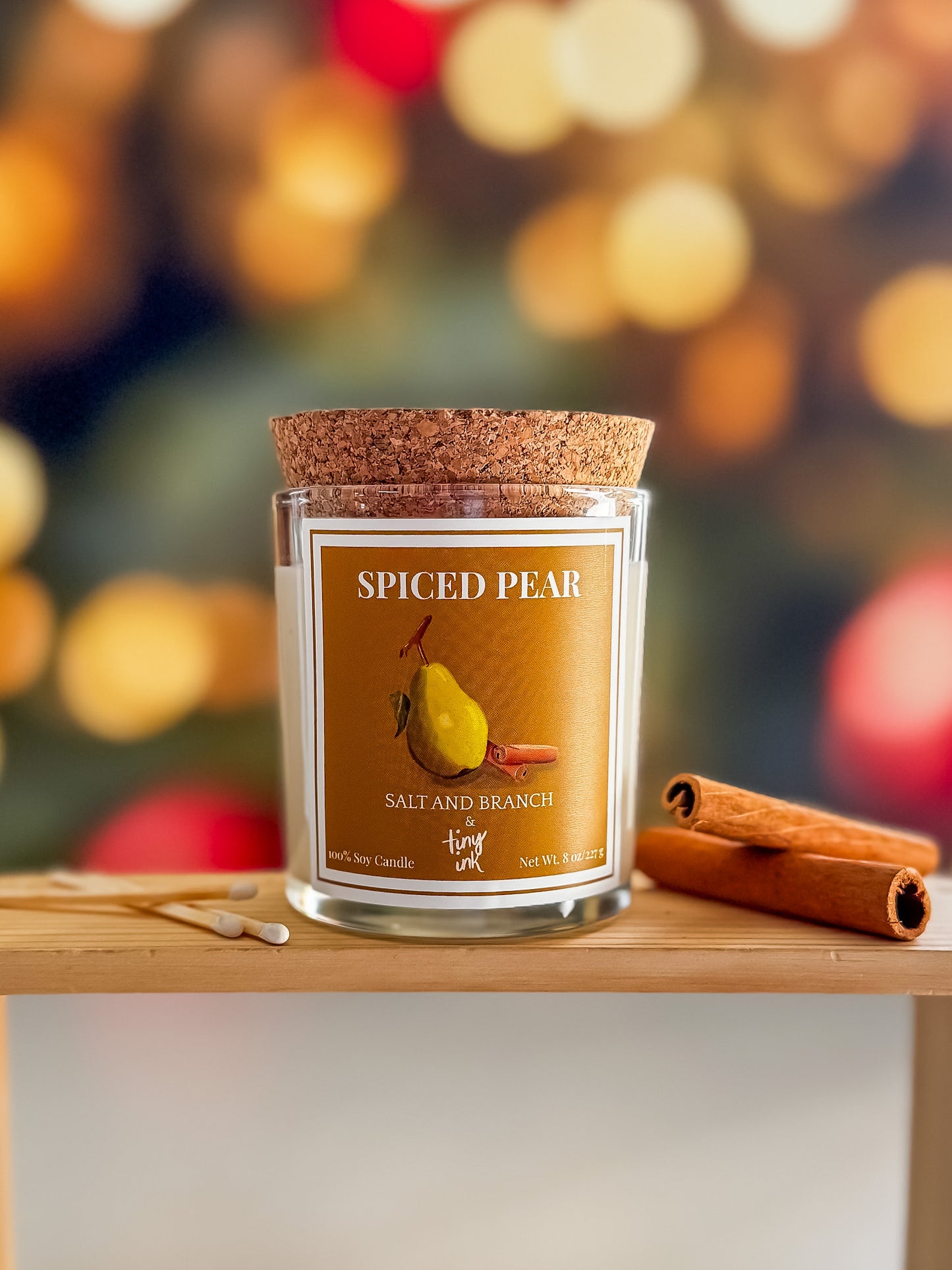 Spiced Pear candle with cinnamon sticks on a wooden surface against a festive background