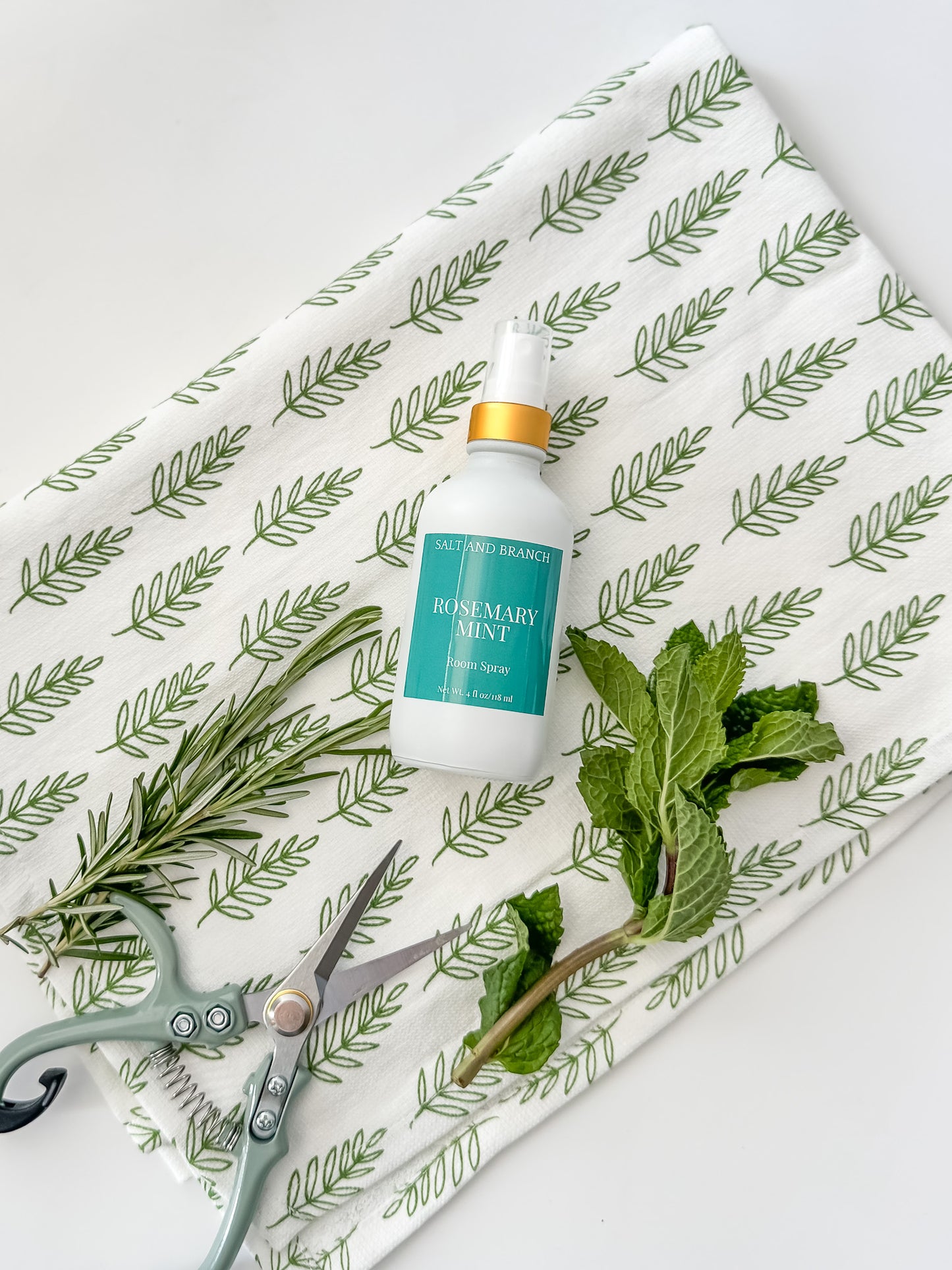 rosemary mint room spray bottle on tea towel with fresh rosemary and mint leaves Salt and Branch