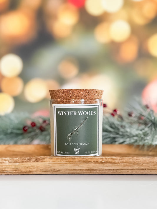 Candle jar called Winter Woods' on a wooden tray with a festive background